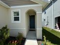 Welcoming front entrance with an arched portico, colorful landscaping, and a dark blue front door at 1648 Heart Bar Rd, Kissimmee, FL 34744