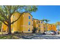 Bright yellow three-story apartment building with on-site parking and mature trees on a sunny day at 4528 Commander Dr # 2013, Orlando, FL 32822