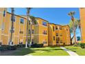 Bright yellow three-story apartment building featuring manicured landscaping, sidewalks and palm trees at 4528 Commander Dr # 2013, Orlando, FL 32822