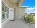Inviting front door framed by a colorful flower bush, window, and covered porch at 53 Zinnia E Ln, Kissimmee, FL 34759