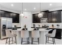 Modern kitchen featuring a spacious island with seating, sleek black cabinets, and stainless steel appliances at 8943 Amelia Downs Trl, Kissimmee, FL 34747