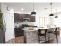 Modern kitchen featuring an island, granite countertops, stainless steel appliances, and dark wood cabinets at 9016 Pyrus St, Kissimmee, FL 34747