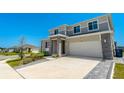 Stylish two-story home showing wide driveway with pavers, manicured landscaping, and a blue sky at 1003 Sugarwood St, Davenport, FL 33837