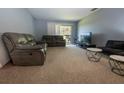 Comfortable living room with plush seating, neutral carpet, and access to an outdoor balcony at 1695 Lee Rd # E215, Winter Park, FL 32789