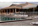 Inviting community pool surrounded by lounge chairs and a white fence with a building in the background at 2615 Autumn Green Dr, Orlando, FL 32822