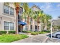 Inviting condo entrance with tropical palm trees, well-maintained landscaping, and covered parking at 3025 Greystone Loop # 302, Kissimmee, FL 34741