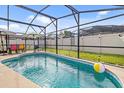 Inviting screened-in pool with clear water and a playful beach ball floating at 7830 Myrtle Oak Ln, Kissimmee, FL 34747