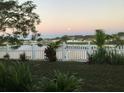 Scenic backyard view with a white picket fence overlooking a serene pond and lush greenery at 954 Hacienda Cir, Kissimmee, FL 34741