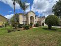 Two-story home featuring an arched entryway, lush green front lawn, and meticulously maintained landscaping at 1960 Aspenridge Ct, Ocoee, FL 34761