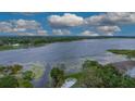 Aerial view of a large lake with trees, homes, and a community pool surrounded by lounge chairs at 2662 Emerald Lake Ct, Kissimmee, FL 34744