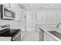 Bright kitchen boasting white cabinets, a center island with sink, and stainless steel oven and microwave at 3773 Deer Ridge Dr, Mount Dora, FL 32757