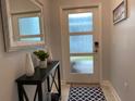 A modern entryway with frosted glass door, console table, decorative mirror, and stylish rug at 637 Ocean Course Ave, Davenport, FL 33896