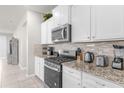 Kitchen with stainless steel appliances, light colored cabinets, and complementing granite countertops at 7211 Oakmoss Loop, Davenport, FL 33837