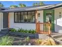 Inviting front porch with wood columns, a green door, black trim and beautifully landscaped garden at 905 W 11Th Ave, Mount Dora, FL 32757
