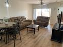 Open-concept living room with laminate flooring and a comfortable sofa set near the dining area at 13226 Galicia St # 103, Orlando, FL 32824