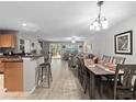 Open-concept living and dining area with wood-look floors, stylish bar seating, and sliding glass doors to the outdoors at 3071 Seaview Castle Dr, Kissimmee, FL 34746