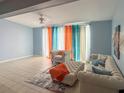Bright living room with tile floors, comfortable seating, and large windows with eye-catching orange and teal curtains at 914 Caribbean Dr, Davenport, FL 33897