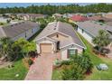 Aerial view of a single Gathering home with a brick driveway, lush landscaping, and well-manicured lawn at 105 Palazzo Ln, Kissimmee, FL 34759