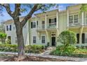 Inviting exterior view of a two-story townhouse with a balcony, a large tree, and well-maintained landscaping at 1303 Artisan E Ave, Celebration, FL 34747