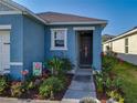 Close-up of the front entry, showing the dark door, landscaping, and well-manicured flowerbeds at 1379 Winter Gray Cir, Deltona, FL 32738