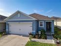 Inviting one-story home featuring a 2-car garage, a well-kept lawn, and colorful garden beds at 1379 Winter Gray Cir, Deltona, FL 32738