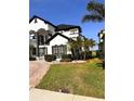 A partial view of a two story home featuring black window trim, dark roof, and well manicured landscaping at 1407 Water Lilly Ln, Kissimmee, FL 34744