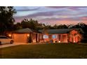 Beautifully lit home with a metal roof and manicured landscaping at dusk at 1849 Kings Point Blvd, Kissimmee, FL 34744