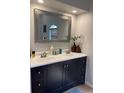 Modern bathroom features dual sinks, a large decorative mirror, and stylish dark blue cabinets at 1920 Triumfo Cir, Kissimmee, FL 34744