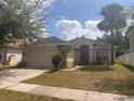 Charming single-story home features a two-car garage, palm tree and a well-maintained lawn at 1948 Bridgeview Cir, Orlando, FL 32824