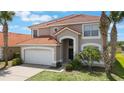 Beautiful two-story home featuring a tile roof, arched entryway, palm trees, and a well-maintained front lawn at 301 Rosso Dr, Davenport, FL 33837