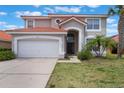 Charming two-story home showcasing a tile roof, arched entrance, and well-manicured lawn with tropical landscaping at 301 Rosso Dr, Davenport, FL 33837
