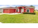 Charming exterior showcasing a well-manicured lawn and a vibrant red facade at 318 Highland Meadows Dr, Davenport, FL 33837