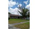 Traditional brick home with a lush green lawn, mature trees, and a welcoming front porch at 3231 Lowndes Dr, Winter Park, FL 32792