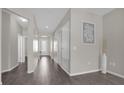 Bright hallway featuring wood flooring and neutral paint, leading to the front door and other rooms at 3366 Puxton Dr, Orlando, FL 32824