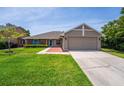 Traditional-style home showcasing a vibrant green lawn, brick accents, and a neutral color scheme at 404 N Sundance Dr, Lake Mary, FL 32746
