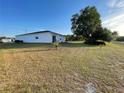 Rear view of a white home with large backyard and mature tree, offering privacy at 505 Peace Way, Poinciana, FL 34759