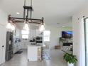 Open-concept kitchen with a large island, modern lighting, and a cozy living space at 6617 Harper Way, Harmony, FL 34773