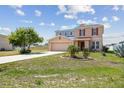 Two-story home features manicured lawn, mature trees, and a two-car garage at 1038 Sabine Pl, Kissimmee, FL 34759