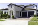 Attractive home exterior with a stone facade, brick driveway, and two-car garage at 15079 Guava Bay Dr, Winter Garden, FL 34787
