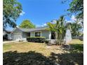 Well-kept gray home featuring a manicured lawn, lush greenery, and healthy palm tree adding curb appeal at 1561 Cypress Woods Cir, St Cloud, FL 34772