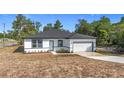 Charming single-story home featuring a well-manicured lawn, a modern door, and an attached garage at 2639 Sw 162Nd Street Rd, Ocala, FL 34473