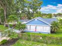 Charming light blue home with lush tropical landscaping and an enclosed front porch at 302 E Drury Ave, Kissimmee, FL 34744
