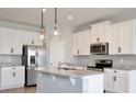 Modern kitchen boasts white cabinets, stainless steel appliances, granite countertops, and pendant lighting at 4327 Silver Creek St, Kissimmee, FL 34744