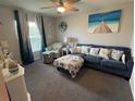 Cozy living room features a plush blue sectional sofa, chair, ottoman, and neutral walls and carpeting at 561 Vittorio Dr, Winter Haven, FL 33884