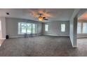 Spacious living room featuring new carpeting, abundant natural light, and a ceiling fan at 804 Wildwood Cir, Port Orange, FL 32127