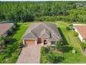 Beautiful aerial view of home with tile roof, brick driveway, lush landscaping, and green space at 819 San Raphael St, Kissimmee, FL 34759