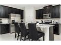 Modern kitchen with stainless steel appliances, granite countertops, and black cabinets at 9038 Pelican Cove Trce, Kissimmee, FL 34747