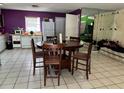 Dining room with round table and tile flooring adjacent to kitchen with white appliances and purple accent wall at 98 Orange Park Blvd, Lake Wales, FL 33898