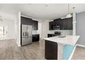 Modern kitchen featuring dark cabinetry, stainless steel appliances, and a stylish breakfast bar at 11843 Fiction Ave, Orlando, FL 32832