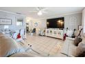 Open living room with white leather couches, tile flooring, and modern white entertainment center at 12539 Orangewood Ct, Tavares, FL 32778